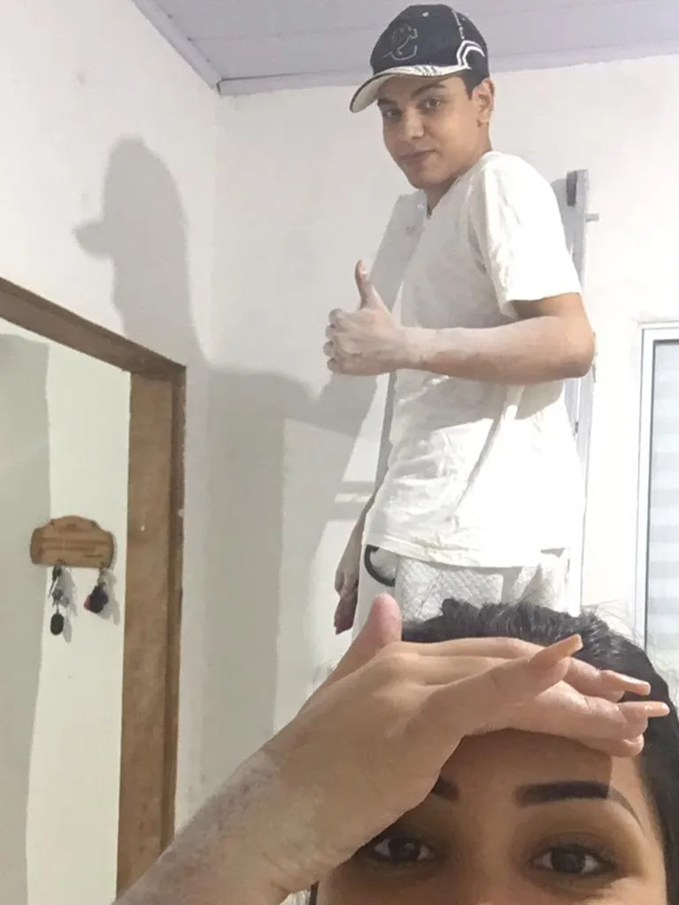 Thiago Hora de boné fazendo sinal de positivo em um quarto simples